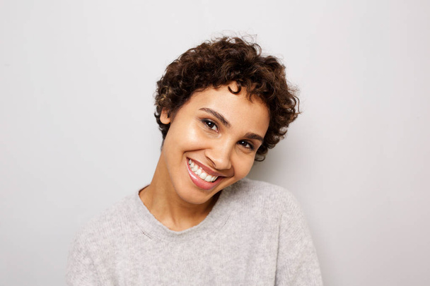 Close up portrait of happy young african american woman smiling by white wall - Foto, imagen