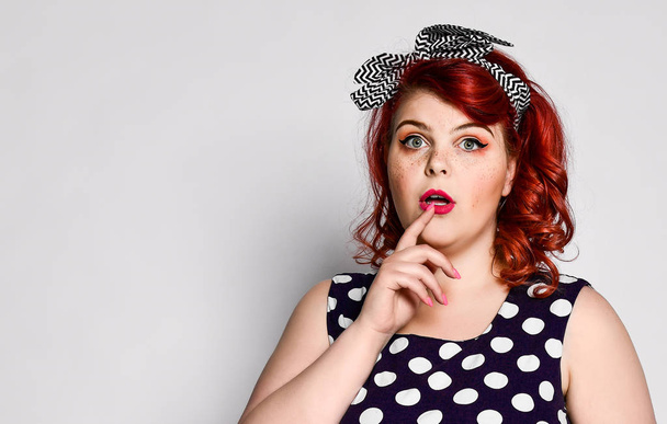 Pin up redhead woman portrait. Beautiful retro female in polka dot dress with red lips and manicure nails and old fashion hairstyle - Photo, Image