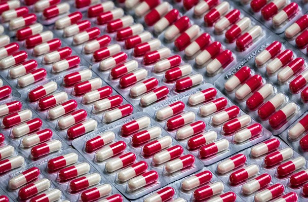 ブリスターパックのピンクホワイトの抗生物質カプセル錠剤。抗生物質耐性の概念。製薬業界。薬局ドラッグストアの背景。薬学の概念。世界のヘルスケア市場.    - 写真・画像