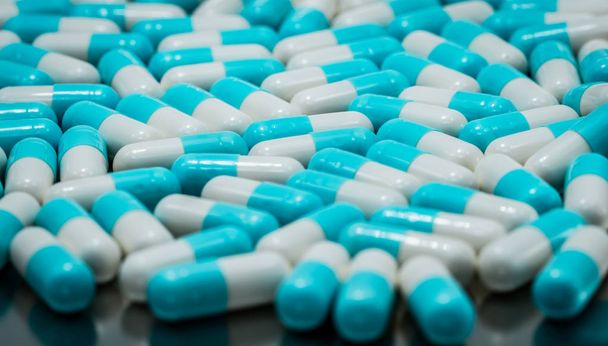 Selective focus on blue and white antibiotic capsule pills. Pharmaceutical industry. Antibiotic drug resistance concept. Pharmaceutics concept. Pastel capsule pills. Pharmacy drugstore background. - Photo, Image