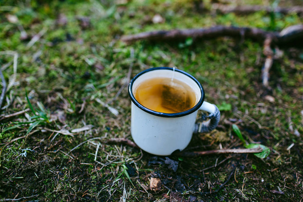Iron mug of tea on the grass - 写真・画像