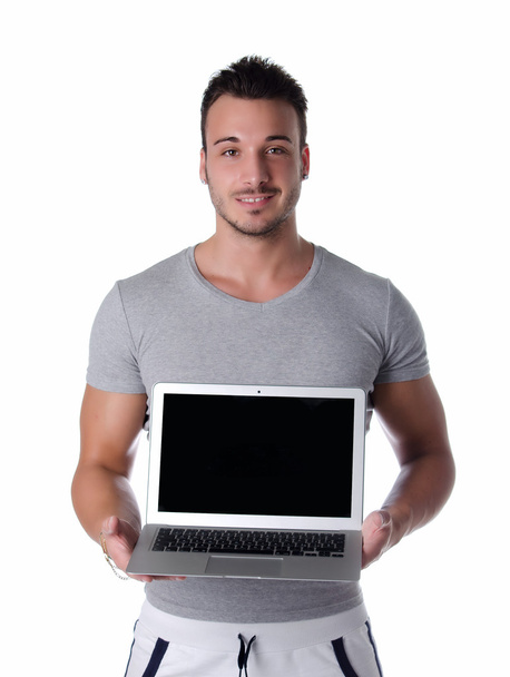 Handsome young man smiling and showing laptop computer - 写真・画像