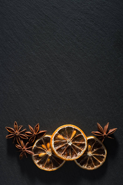μια σύνθεση από αποξηραμένα λεμόνια και γλυκάνισο στο φυσικό σχιστόλιθο - Φωτογραφία, εικόνα