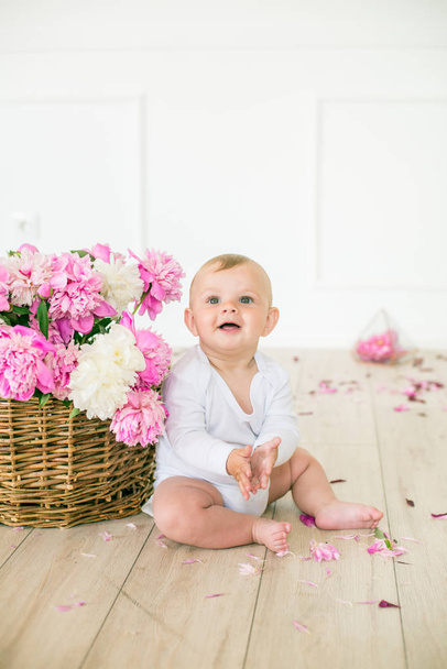 little cute baby with a big basket of beautiful spring pink and white peonies - Photo, image