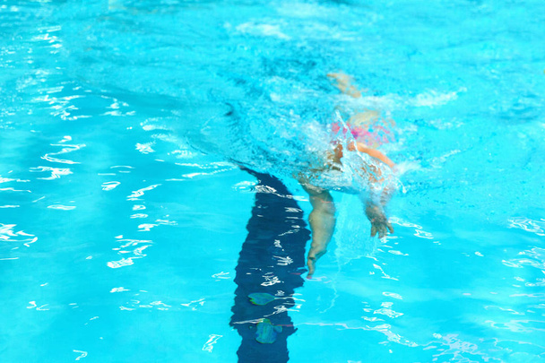 A young boy pounds in the pool. - Zdjęcie, obraz