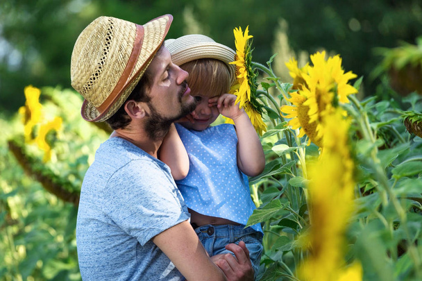 Happy father and daughter are hugging in the field of sunflowers - Valokuva, kuva