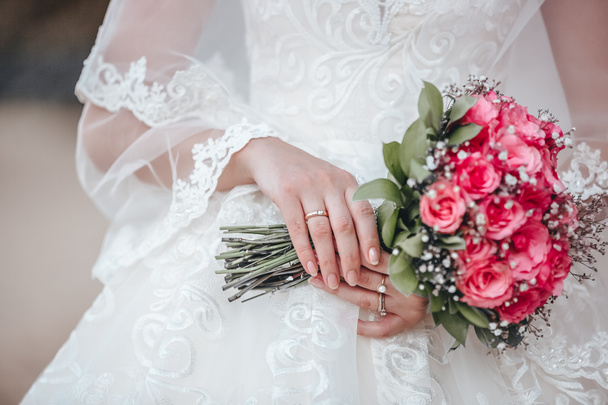 A menyasszony esküvői csokrot tart rózsaszín virágokból. - Fotó, kép