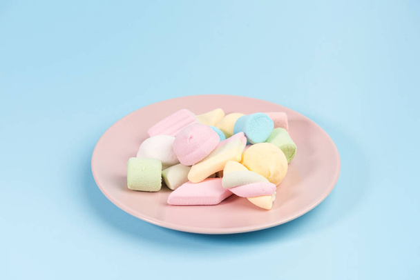 Pink plate with marshmallow isolated on blue background. - Fotoğraf, Görsel