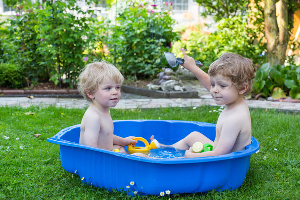 Dos hermanos que se divierten con el agua en verano
 - Foto, Imagen