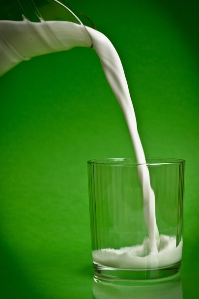 Despejando leite de um jarro em um copo
 - Foto, Imagem