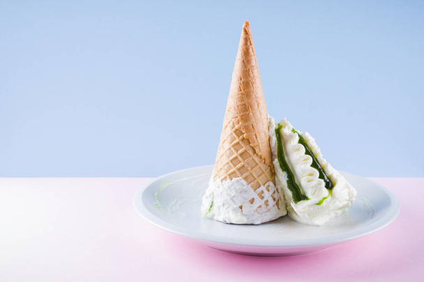 Ice cream cone on pink blue background, summer concept. Dessert with jam on green plate. Waffle cone with ice cream in pastel colors. Copy space - 写真・画像
