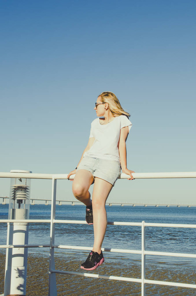 Young woman sitting near ocean and looking forward  - Φωτογραφία, εικόνα