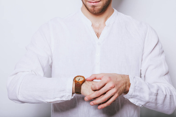 Een man in een elegant wit overhemd met een klok op zijn hand - Foto, afbeelding