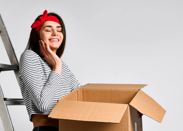 Delivery, relocation and unpacking. Smiling young woman holding cardboard box isolated on white background - Фото, зображення