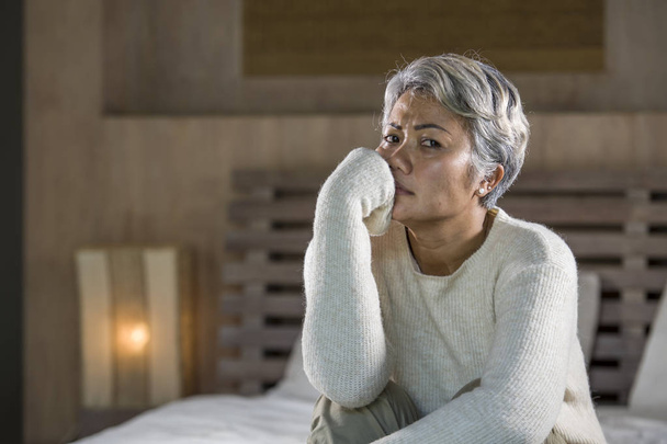 dramatic lifestyle home portrait of attractive sad and depressed middle aged woman with grey hair on bed feeling upset suffering depression and anxiety - Foto, afbeelding