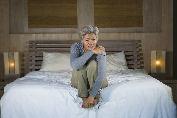 dramatic lifestyle home portrait of attractive sad and depressed dramatic lifestyle home portrait of attractive sad and depressed middle aged woman with grey hair on bed feeling upset suffering depres - Photo, Image