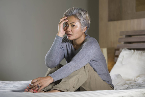  dramatický životní styl domácí portrét atraktivní smutné a depresivní ženy středního věku s šedými vlasy na posteli pocit deprese a úzkosti - Fotografie, Obrázek