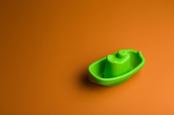 little green plastic toy ship on the yellow background with copy space. - Fotografie, Obrázek