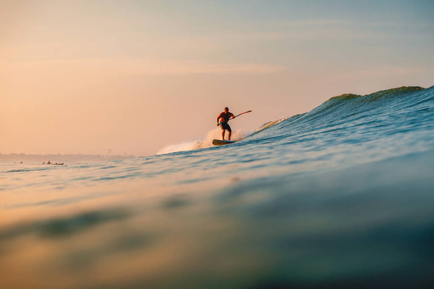 April 12, 2019. Bali, Indonesia. Stand Up Paddle surfer ride on ocean wave. Stand Up Paddle surfing at waves in Bali - 写真・画像