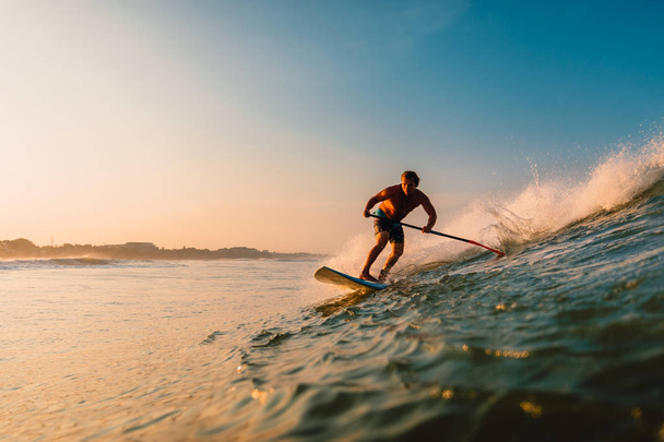 April 12, 2019. Bali, Indonesia. Stand Up Paddle surfer ride on ocean wave. Stand Up Paddle surfing at waves in Bali - Photo, Image