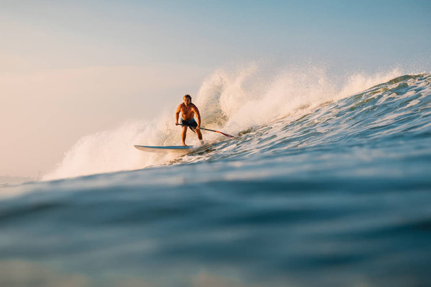 12 aprile 2019. Bali, Indonesia. Stand Up Paddle cavalcare surfista sull'onda dell'oceano. Stand Up Paddle surf alle onde a Bali
 - Foto, immagini