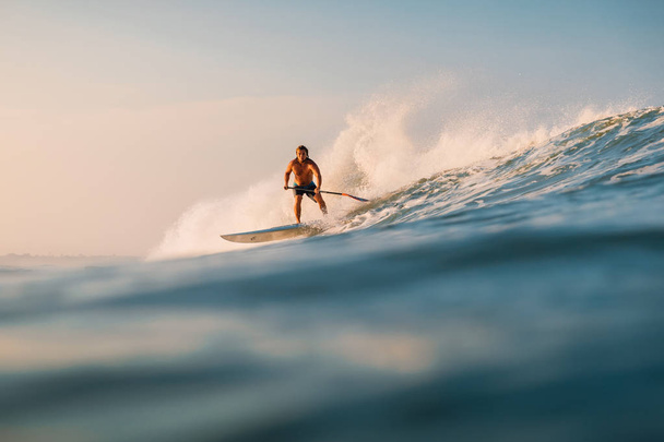 2019. április 12. Bali, Indonézia. Állj fel evezz szörfös lovagolni az óceán hullám. Állj fel lapát szörfözés a hullámok Bali - Fotó, kép