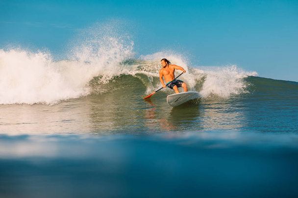 12 de abril de 2019. Bali, Indonésia. Stand Up Paddle surfista passeio na onda do oceano. Stand Up Paddle surfando em ondas em Bali
 - Foto, Imagem
