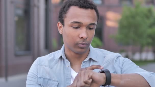 Αφρικανός άνθρωπος χρησιμοποιώντας έξυπνο ρολόι υπαίθριο - Πλάνα, βίντεο