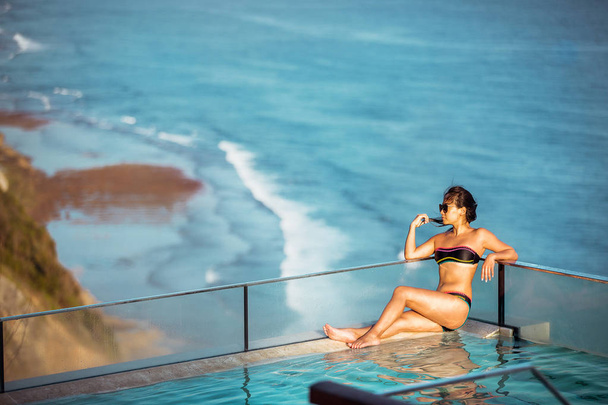 Girl swims in the hotel pool over the sea The Edge Bali - Uluwatu  - Bali - Indonesia - Zdjęcie, obraz
