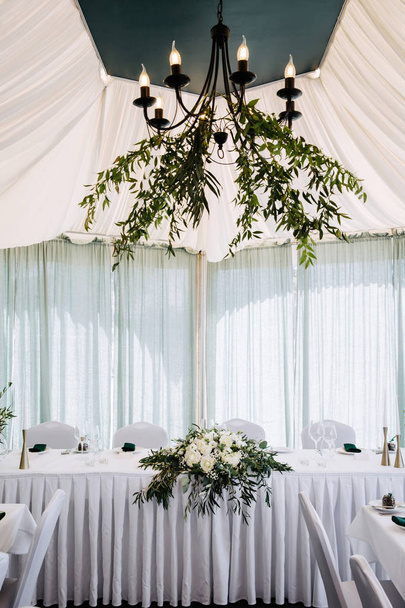 Wedding restaurant interior table, no people. White table set decorated with green leaves and white peonies. - Zdjęcie, obraz