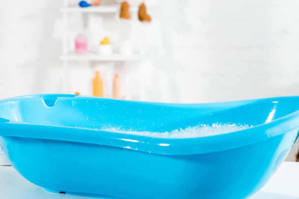 banheira de bebê azul com água e espuma de banho no banheiro
  - Foto, Imagem
