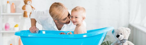 colpo panoramico di madre bionda vicino felice figlio del bambino fare il bagno
  - Foto, immagini