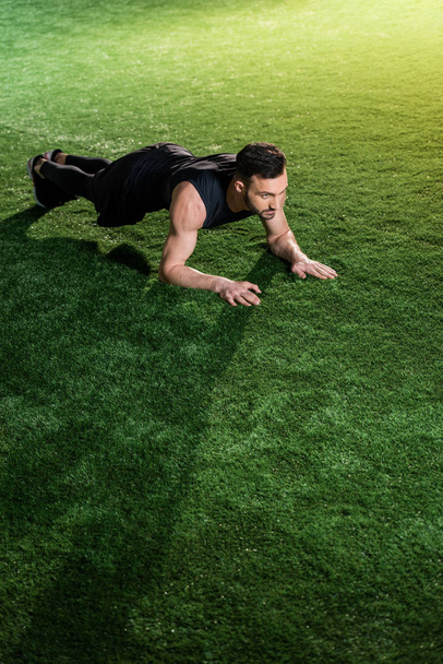 handsome athletic man doing plank exercise on green grass  - Foto, Imagen
