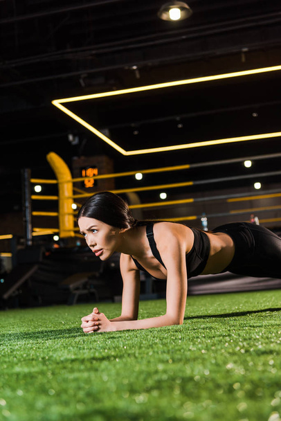 selective focus of attractive woman doing plank exercise on grass  - Foto, afbeelding