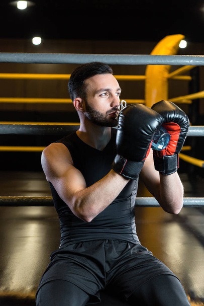 handsome man in boxing gloves drinking water in sports center  - Фото, зображення