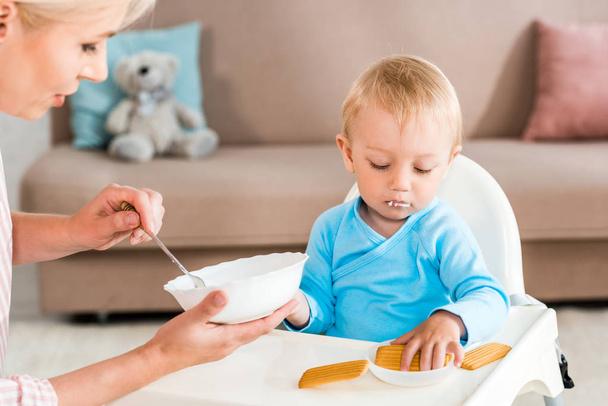 selektivní zaměření matky na misku s dětskou stravou v blízké roztomilé batole synu doma  - Fotografie, Obrázek