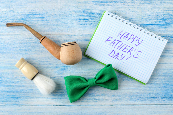 happy vader Day. tekst en decoratieve mannen tie Butterfly en rookpijp op een licht blauwe houten achtergrond. Top View - Foto, afbeelding