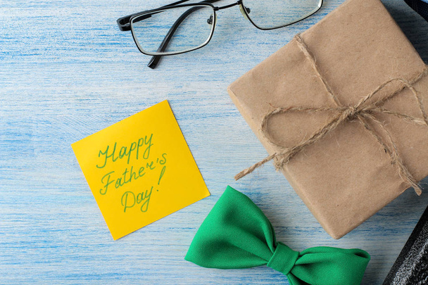 Счастливого дня отца. мужские аксессуары галстук духи, очки и светло-синий деревянный фон. вид сверху
 - Фото, изображение