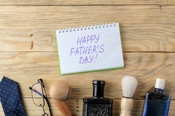 Happy father's day. text in a notebook and various men's accessories on a natural wooden background. top view - Photo, Image