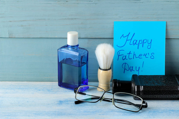 Babalar günün kutlu olsun. metin ve erkek aksesuarları, kravat, parfüm ve gözlük açık mavi ahşap arka plan üzerinde. - Fotoğraf, Görsel
