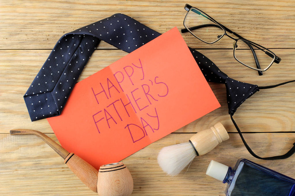 Happy father's day. Text on paper and various men's accessories on a natural wooden background. top view - Foto, Bild