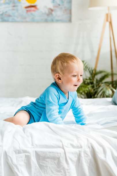 surprised kid lying on bed with white bedding at home  - Foto, immagini