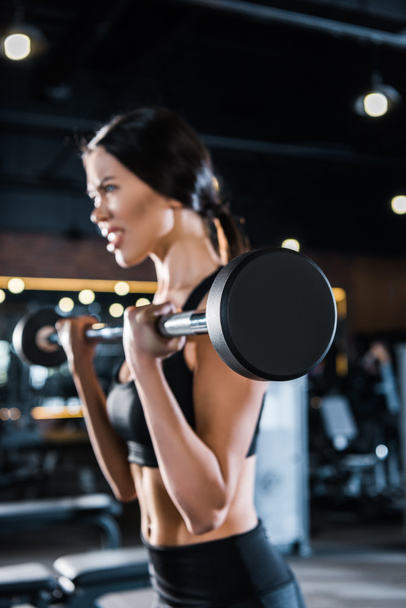 selective focus of strong young woman exercising with heavy barbell in gym  - Φωτογραφία, εικόνα