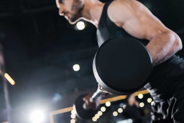 selective focus of strong man exercising with heavy barbell in gym  - Fotografie, Obrázek