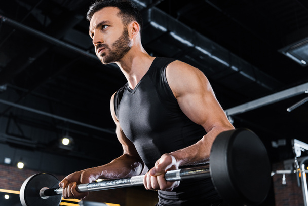 niski kąt widzenia silnego mężczyznę ćwiczącego z ciężkim Brzana w siłowni  - Zdjęcie, obraz