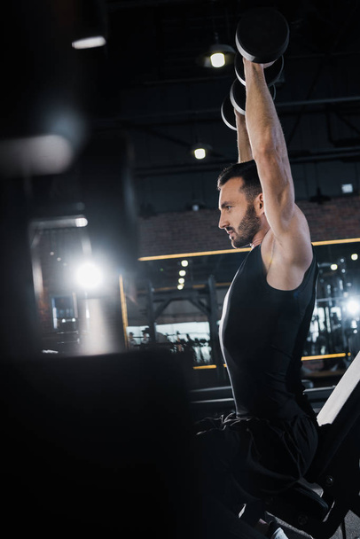 enfoque selectivo de hombre atlético guapo haciendo ejercicio con pesas en el gimnasio
  - Foto, Imagen
