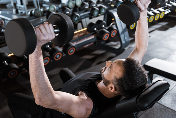 vista aérea del hombre fuerte guapo haciendo ejercicio con pesas en el gimnasio
  - Foto, Imagen