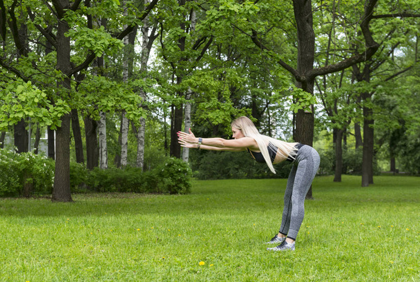 λεπτή σπορ κορίτσι στο πάρκο, κάνει τις στροφές μπροστά - Φωτογραφία, εικόνα