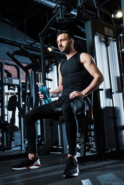 low angle view of sportsman in sportswear holding sport bottle in gym  - Photo, Image