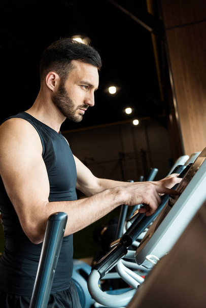 selective focus of handsome athletic man pointing with finger while standing near exercise bikes  - Foto, Imagem
